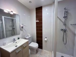 a bathroom with a shower and a toilet and a sink at Hôtel du Cheval Rouge in Versailles +23 photos