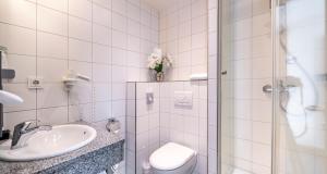 a bathroom with a toilet and a sink and a shower at PLAZA INN Heidehof in Hermannsburg +74 photos