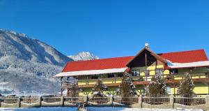 a lodge in the snow with mountains in the background at Maricom Home in Zărneşti