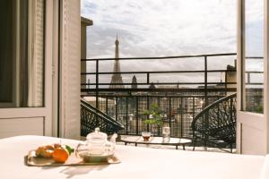 a table with a plate of fruit and a view of the eiffel tower at Hôtel Atala Champs Elysees in Paris