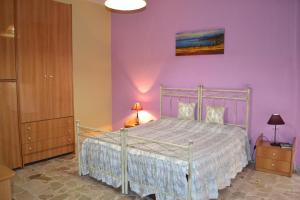 a bedroom with a bed and a purple wall at Case Porta San Salvatore Sciacca in Sciacca