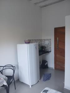 a white refrigerator in a room with a table at Kitinete encantadora in Arraial do Cabo