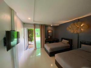 a bedroom with two beds and a flat screen tv at Wang nam yen hill วังน้ำเย็นฮิลล์ in Ban Mai
