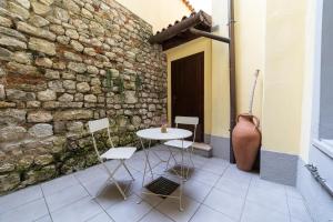 a table and chairs in front of a stone wall at Alla Casa Medievale in Cividale del Friuli