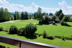 a field of green grass with a fence and a house at Ferienappartement Greta in Lechbruck