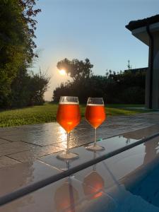 two wine glasses sitting on a table near a pool at Albarella Family Villa with Private Pool and Garden in Isola Albarella