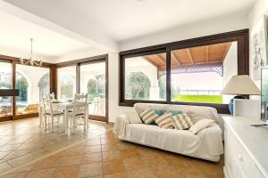 a living room with a white couch and a table at Albarella Family Villa with Private Pool and Garden in Isola Albarella