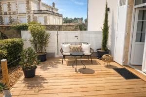 an outdoor patio with a chair and a table at La Villa Blanche Appart hôtel in Salles