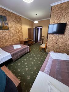 a hotel room with two beds and a flat screen tv at Гостиница TERRA in Almaty