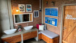 a bathroom with two sinks on a brick wall at Shelter Hostel Malang in Malang +17 photos