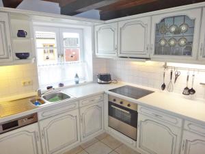 a white kitchen with white cabinets and a sink at Rosenhaus in Kappeln