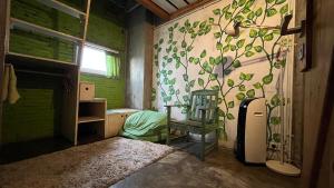a bathroom with a green wall with a tree mural at Shelter Hostel Malang in Malang