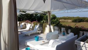 a patio with white chairs and an umbrella at Villa Rosamarina in Rosa Marina