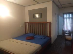a bedroom with a bed with blue sheets and a window at Cool feel rest and cafe in Nuwara Eliya