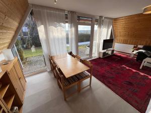a living room with a wooden table and a large window at Eulenburg am Reuthsee Nurdachhaus mit Garten in Sulzdorf an der Lederhecke