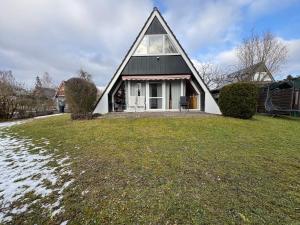 a small house with a gambrel roof on a yard at Eulenburg am Reuthsee Nurdachhaus mit Garten in Sulzdorf an der Lederhecke