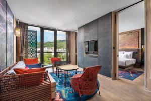 a living room with a couch and chairs and a bed at Hotel Indigo Phuket Patong by IHG in Patong Beach