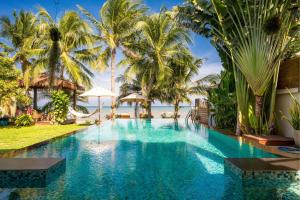 a swimming pool in a resort with palm trees at Baan SanSuk Pranburi - Beach Front & Pool Villa in Pran Buri