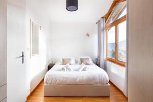 a white bedroom with a bed and a window at Le Chalet Panoramique Jaccuzi Parking Vue Montagne in Munster