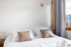 a white bed with two pillows and a window at Le Chalet Panoramique Jaccuzi Parking Vue Montagne in Munster