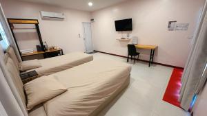a room with two beds and a desk and a television at NICHA Cafe' & Resort in Ban Thap Chek Ha