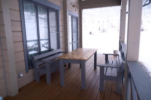 a porch with a wooden table and a bench at MATRYOSHKA HOUSE 2nd GUEST HOUSE in Yoichi