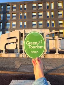 a person holding a green tourism coalition sign in front of a building at Aloft by Marriott Aberdeen TECA in Aberdeen +28 photos