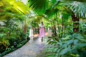 a woman in a pink dress walking through a garden at Grand Hyatt Dubai Resort & Waterpark in Dubai +19 photos