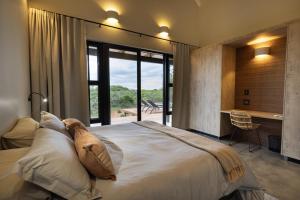 a bedroom with a large bed with a large window at Villa Kolobe in Hoedspruit