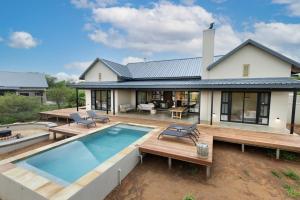 a home with a swimming pool and a house at Villa Kolobe in Hoedspruit