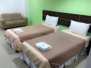 two beds in a hotel room with a chair at Diamond Bangkok Apartment in Bangkok