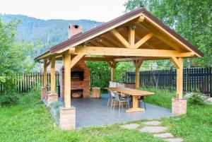 a wooden gazebo with a picnic table in a yard at Chalet M 1 in Lunca Bradului