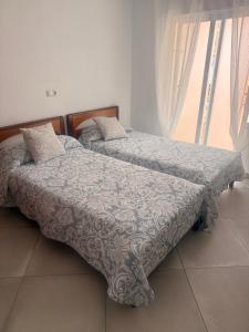 two twin beds in a room with a window at Habitación Doble a 100 m de la Playa in Benidorm +7 photos