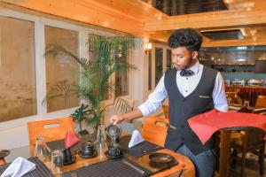 a man in a tuxedo standing next to a table at Queens Lake Cabin in Nuwara Eliya