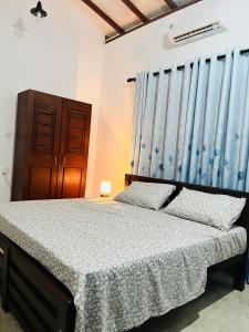 a bedroom with a bed and a blue curtain at Manthraa Holiday Apartment in Ratgama Hegoda