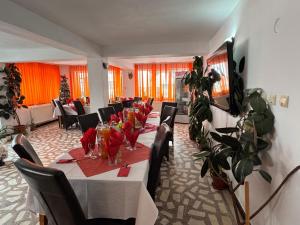 a dining room with a long table with chairs and glasses at Casa Andu in Dâmbovicioara