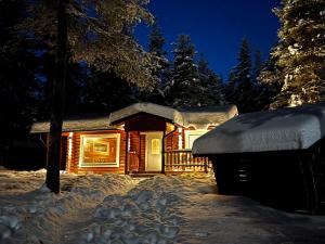 a log cabin in the snow at night at Kaupinmaja, Ylläs, Äkäslompolo, Lapland - Log Cabin with Lake and Fell Scenery in Äkäslompolo