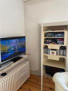 a living room with a tv and a shelf with dvds at Conciergerie du château in Gevingey