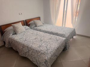 two twin beds in a room with a window at Habitación Doble a 100 m de la Playa in Benidorm