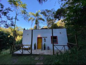 a small white house with a table in front of it at Chalé na floresta com varanda in Ouro Preto