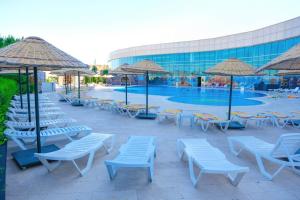 a pool with chairs and umbrellas next to a building at BİG THERMAL Spa Resort in Kalankaldı