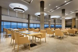 a dining room with tables and chairs and windows at BİG THERMAL Spa Resort in Kalankaldı