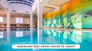 a swimming pool with chairs and a painting on the wall at BİG THERMAL Spa Resort in Kalankaldı