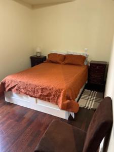 a bed with an orange comforter in a bedroom at Caniço Easy Stay in Caniço