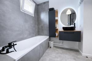 a bathroom with a tub and a sink and a mirror at Escapade du Stade BY UTA HOUSE in Saint-Denis +18 photos