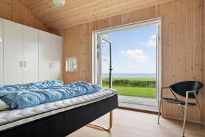 a bedroom with a large window and a bed and a chair at 20422-Samso-Egernvej-16 in Ballen