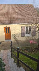 a white house with a brown door and a fence at L'ALPETTE maison 3 pièces 2 chambres tout confort in Vernouillet
