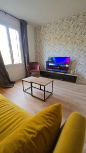 a living room with a couch and a tv at L'ALPETTE maison 3 pièces 2 chambres tout confort in Vernouillet