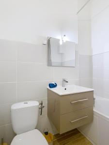 a white bathroom with a toilet and a sink at Le Pianiste in Voiron