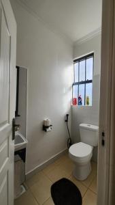 a white bathroom with a toilet and a window at Kamakis Motel & Lounge in Ruiru